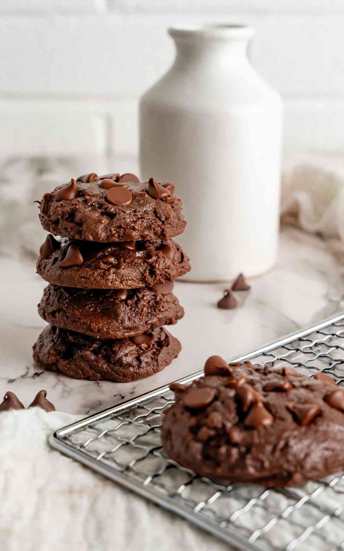 A stack of fudge cookies next to a cooling rack.
