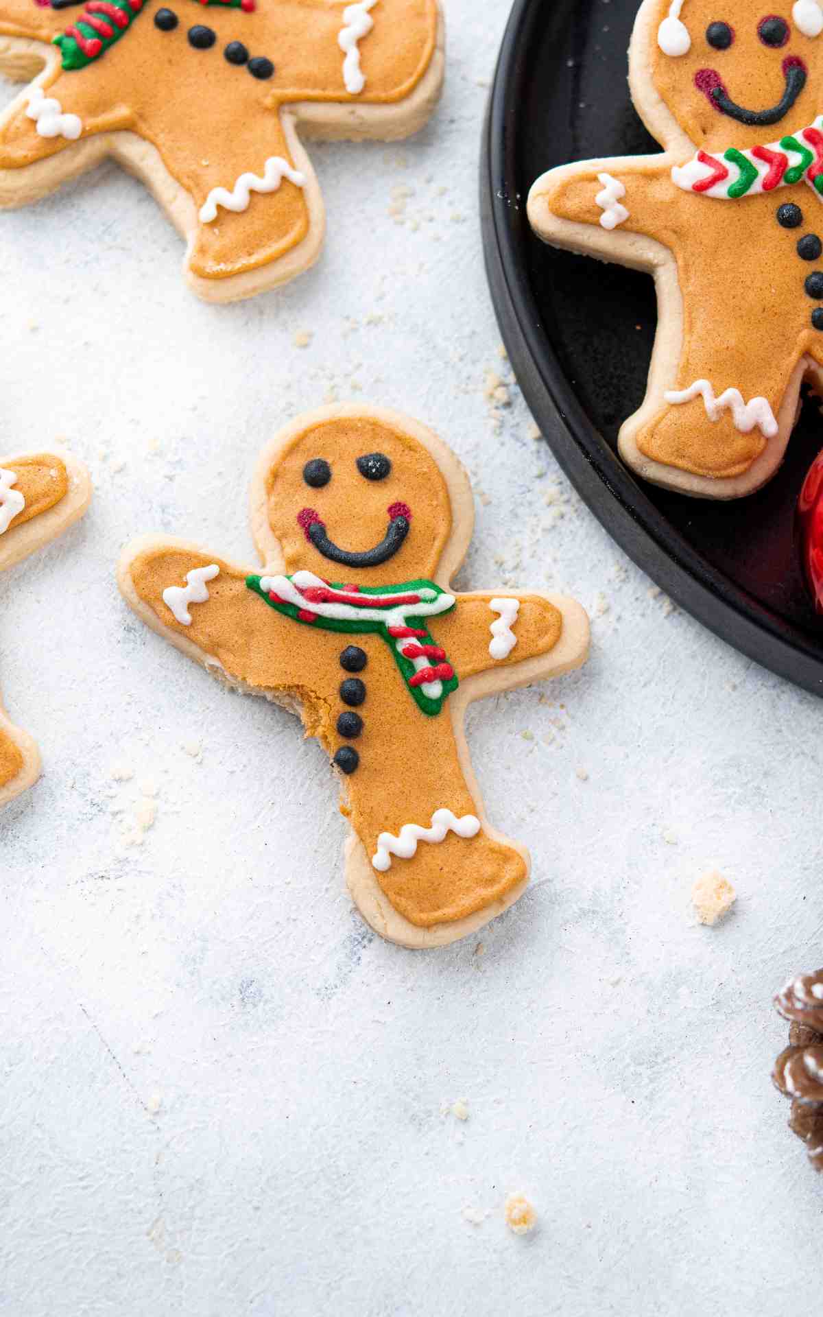 Gingerbread man shaped sugar cookie decorated with royal icing with a bite taken out of it.