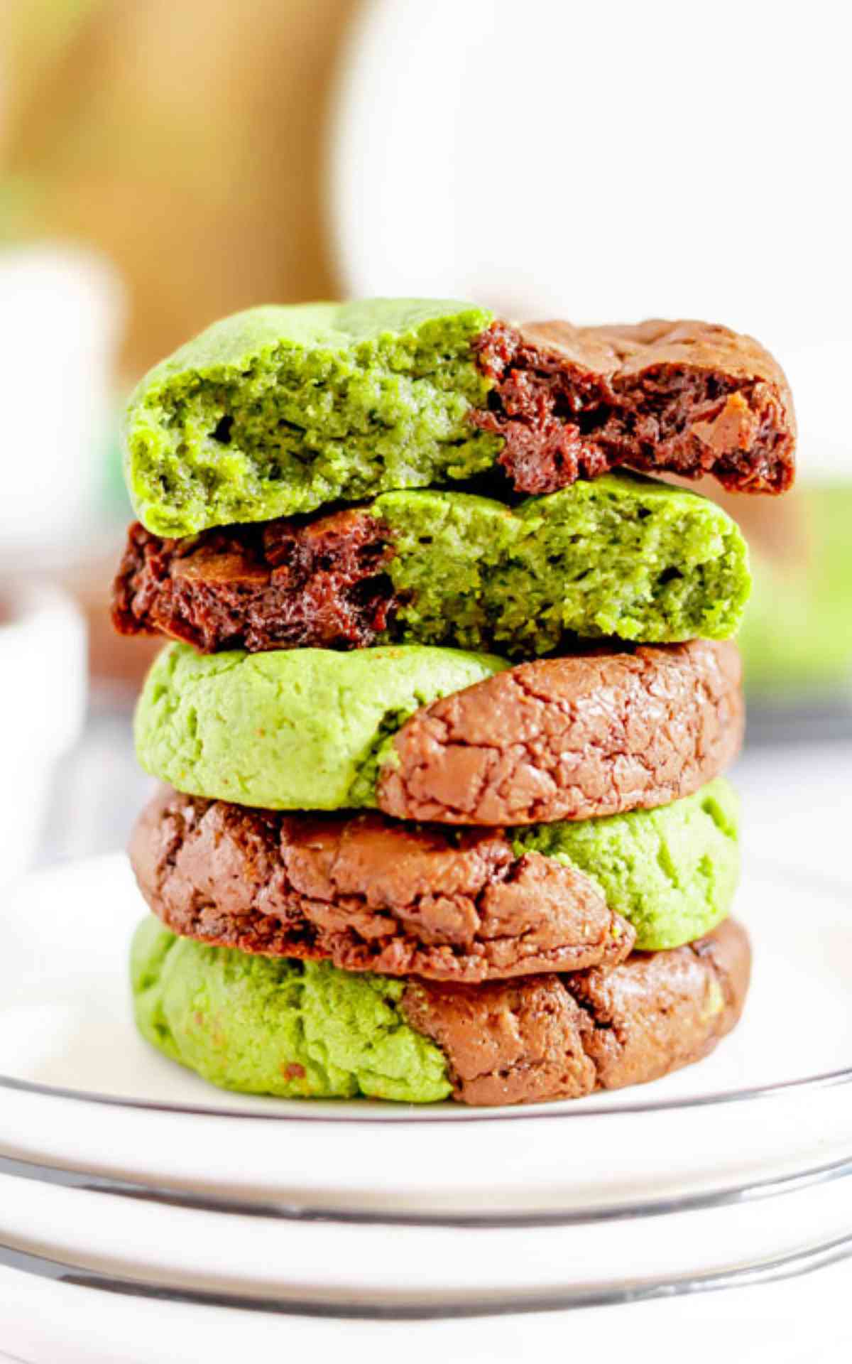 Matcha Cookies stacked on a plate with a cookie cut in half on top.