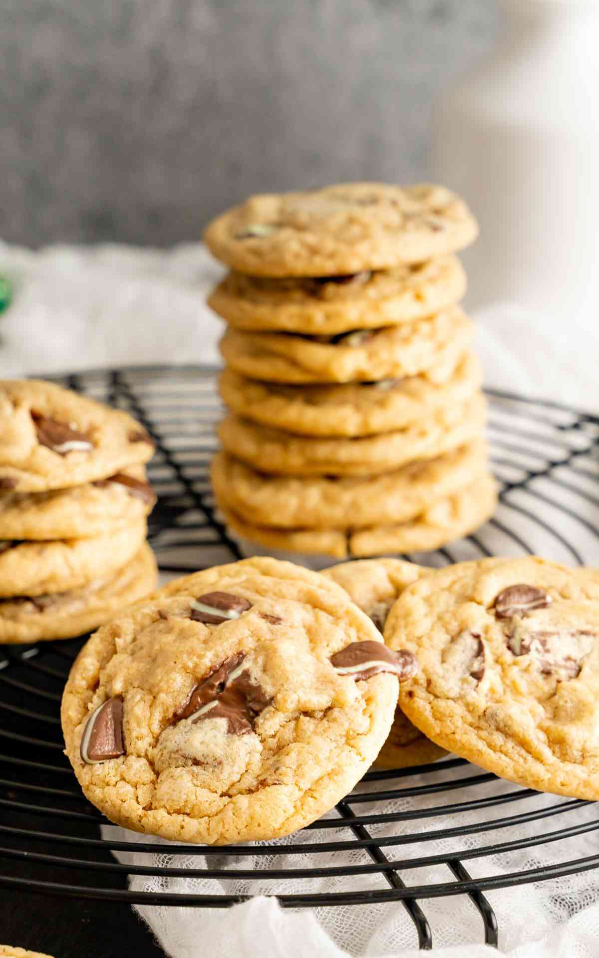 Stacked mint chocolate chip cookies on a black drying rack.