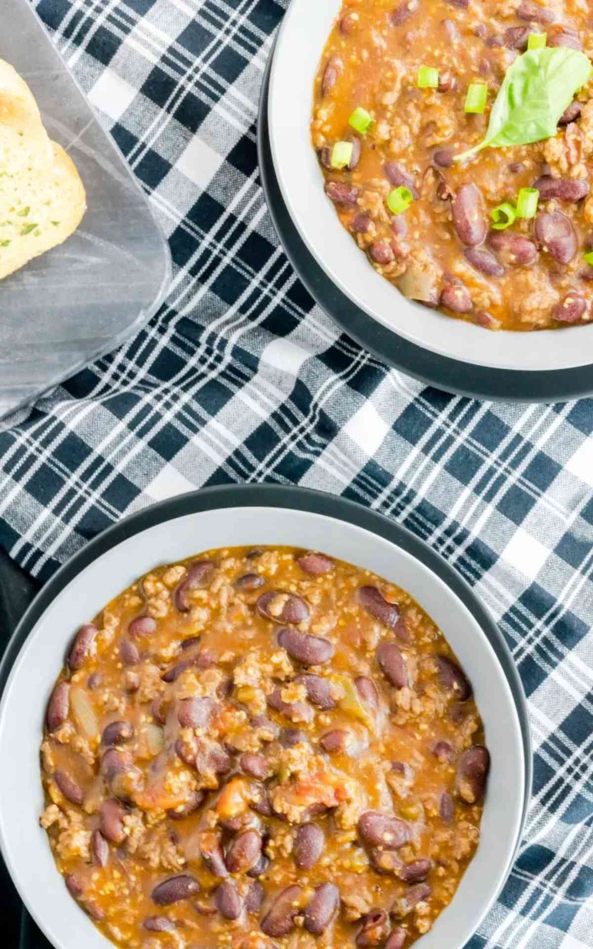Two bowls of firehouse chili on a checkered napkin.