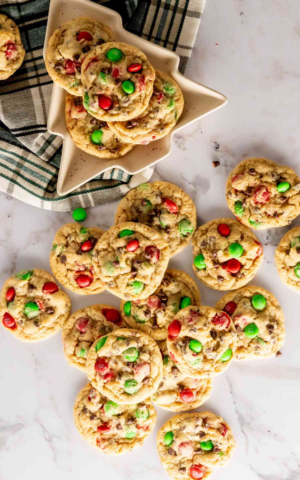 Birdseye view of a Christmas shaped plate with Christmas cookies with cookies surrounding in the counter.