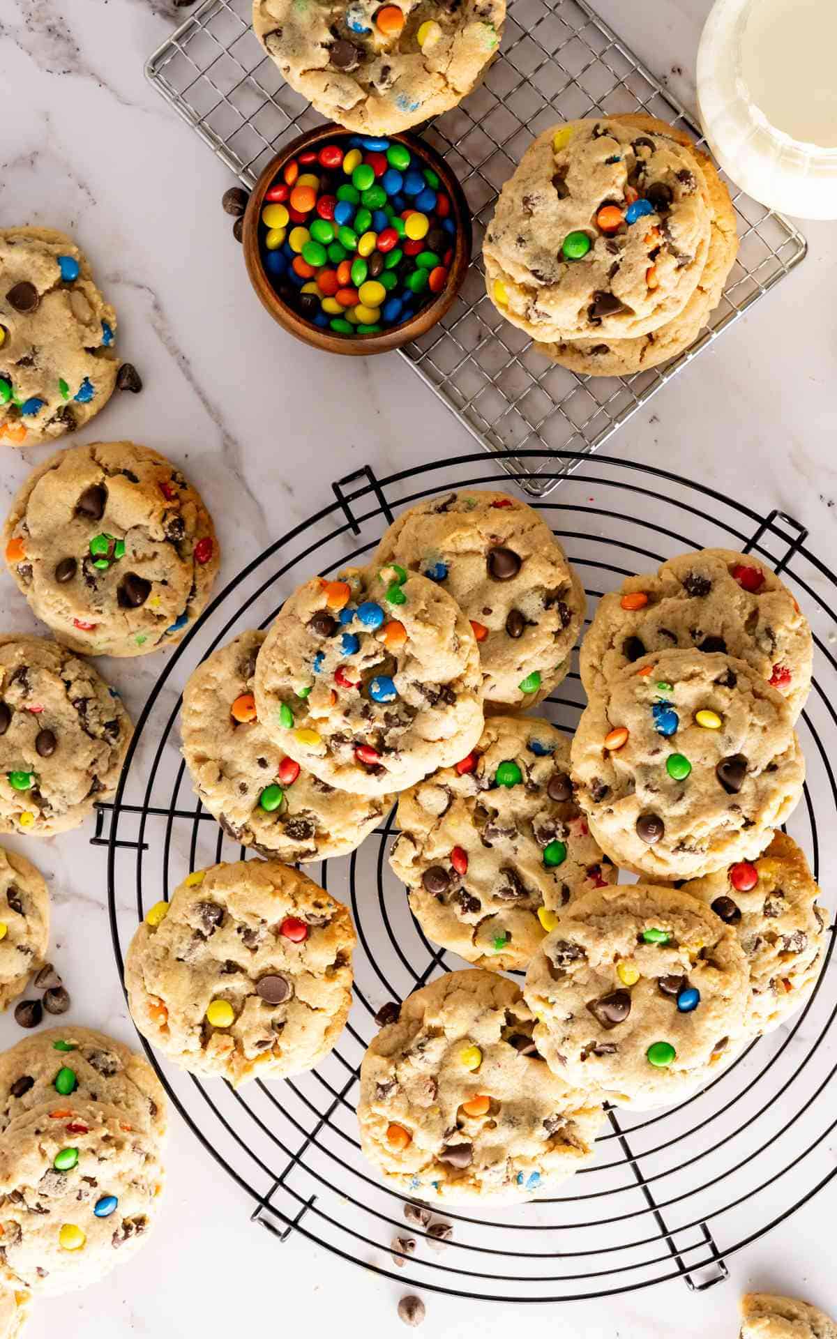 Birdseye view of peanut butter cookies on a cooling rack packed with M&Ms and chocolate chips.
