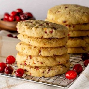 Two stacks of cranberry orange cookies on a cooling rack with fresh cranberries.