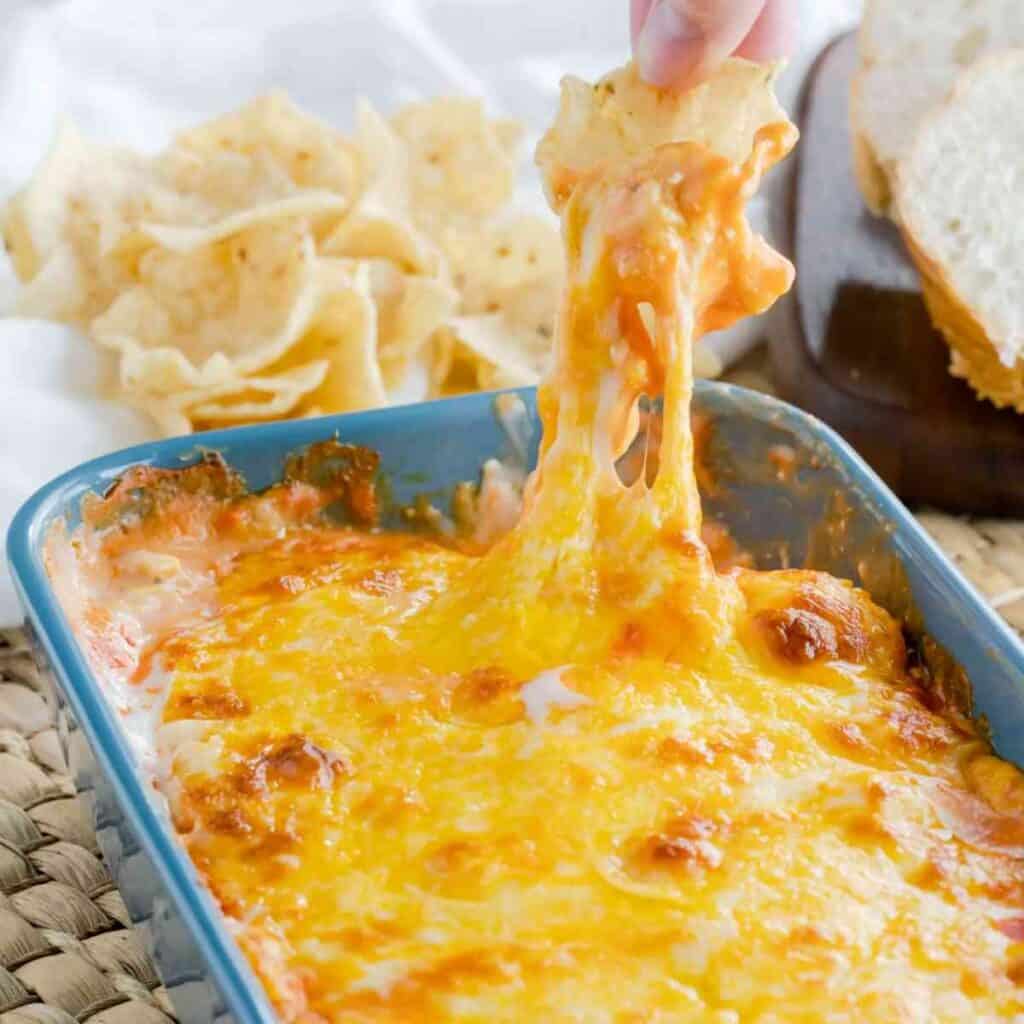 A tortilla scoop in a dish of buffalo chicken dip.