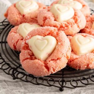 A pile of strawberry cake mix cookies with a white chocolate heart in the center.