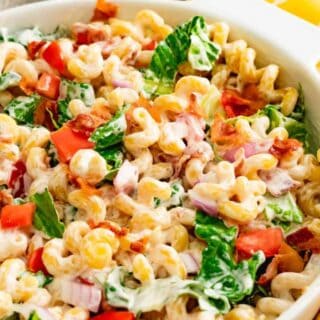 A close up of blt salad with pasta in a white serving dish with fresh ingredients.