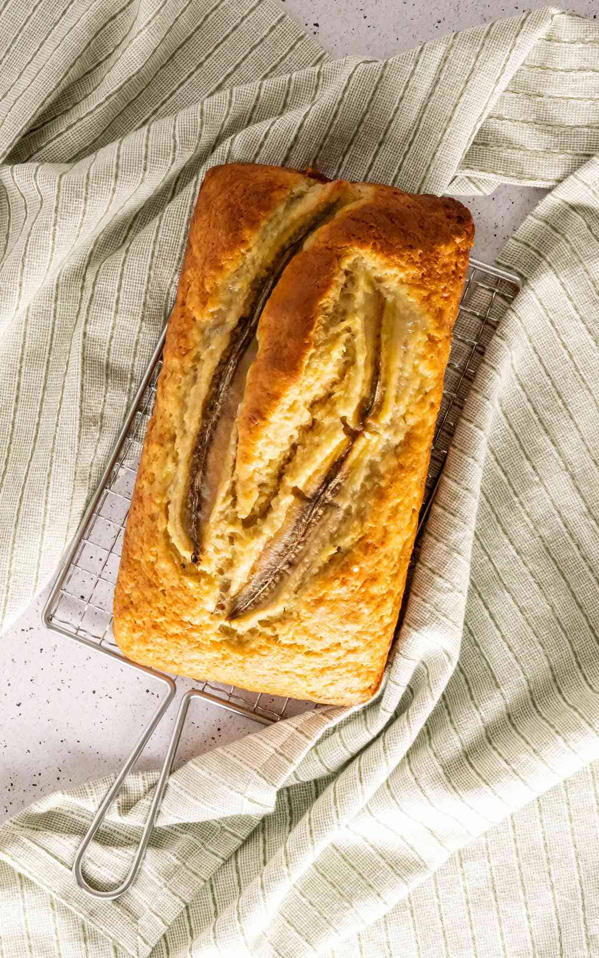 A loaf of 4 ingredient banana bread with a split banana baked into the top.