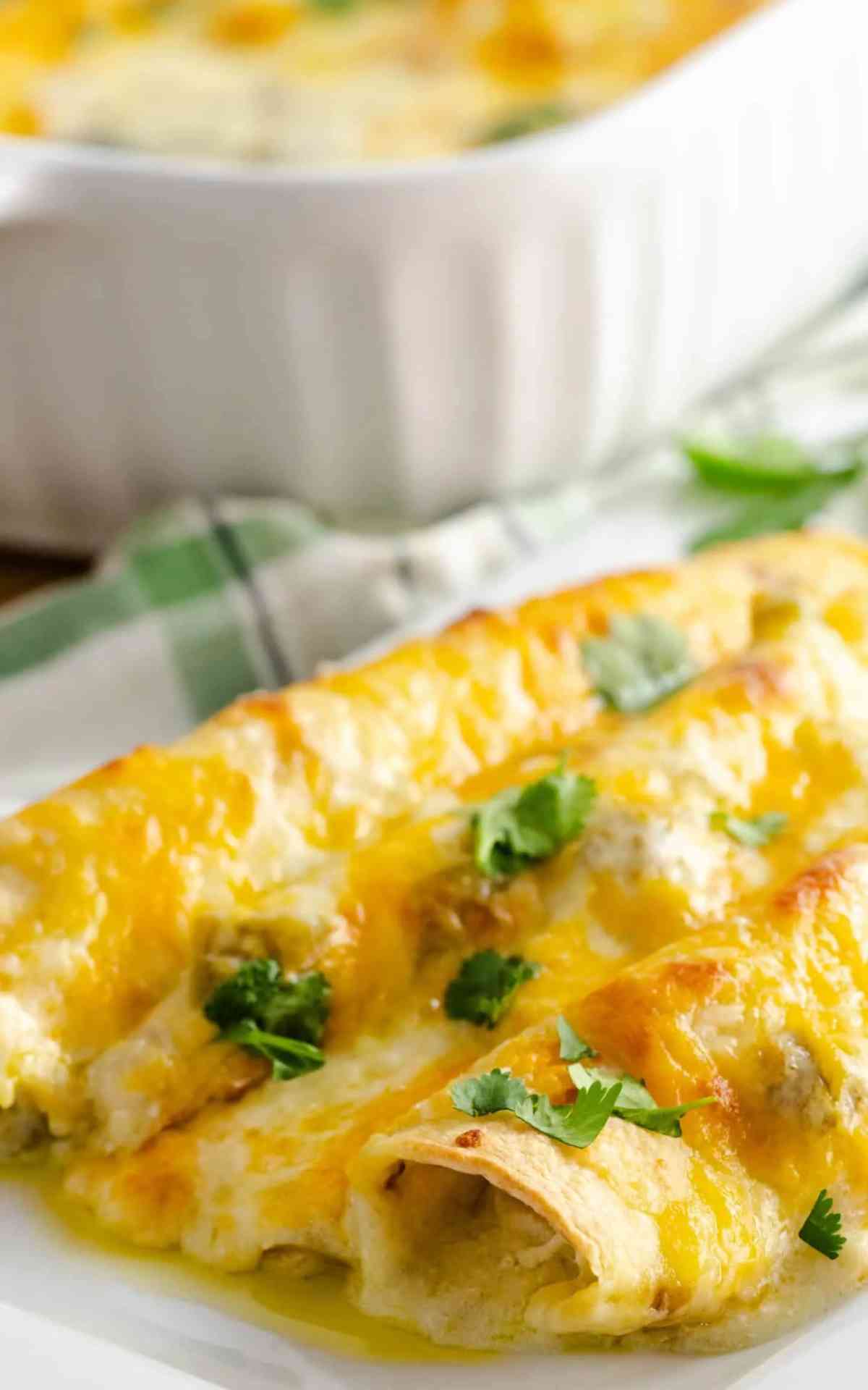 A serving of white chicken enchiladas topped with cilantro on a white plate.