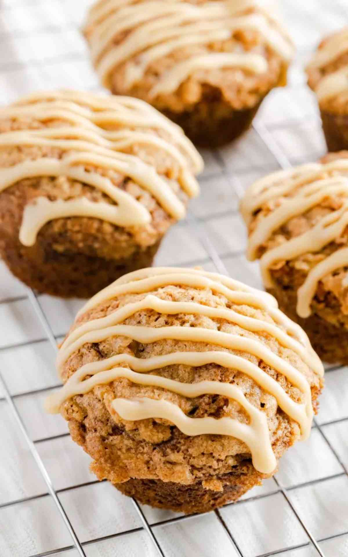 A couple of banana caramel muffins on a wire rack drizzled with caramel.