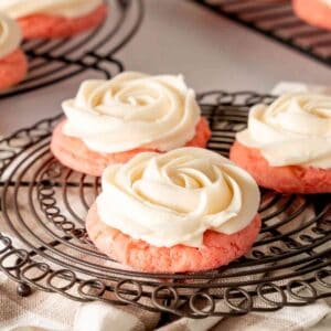 Piped rosettes on pink lemonade cookies on cooling racks.