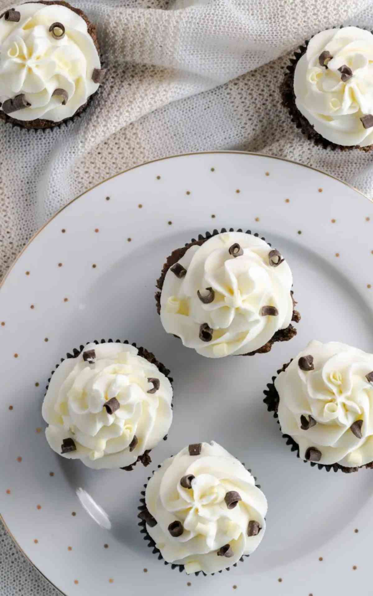Piped Vanilla buttercream frosting on chocolate cupcakes garnished with chocolate curls.