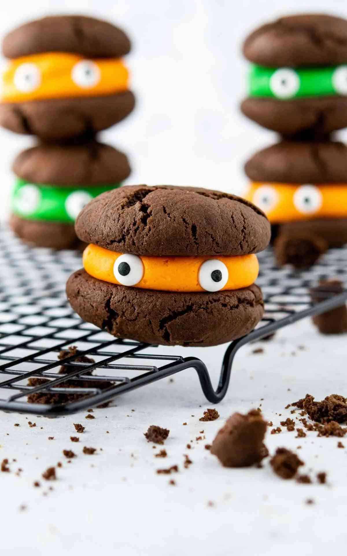 Cookie closeup of Chocolate sandwich cookie with orange filling and candy eyes.