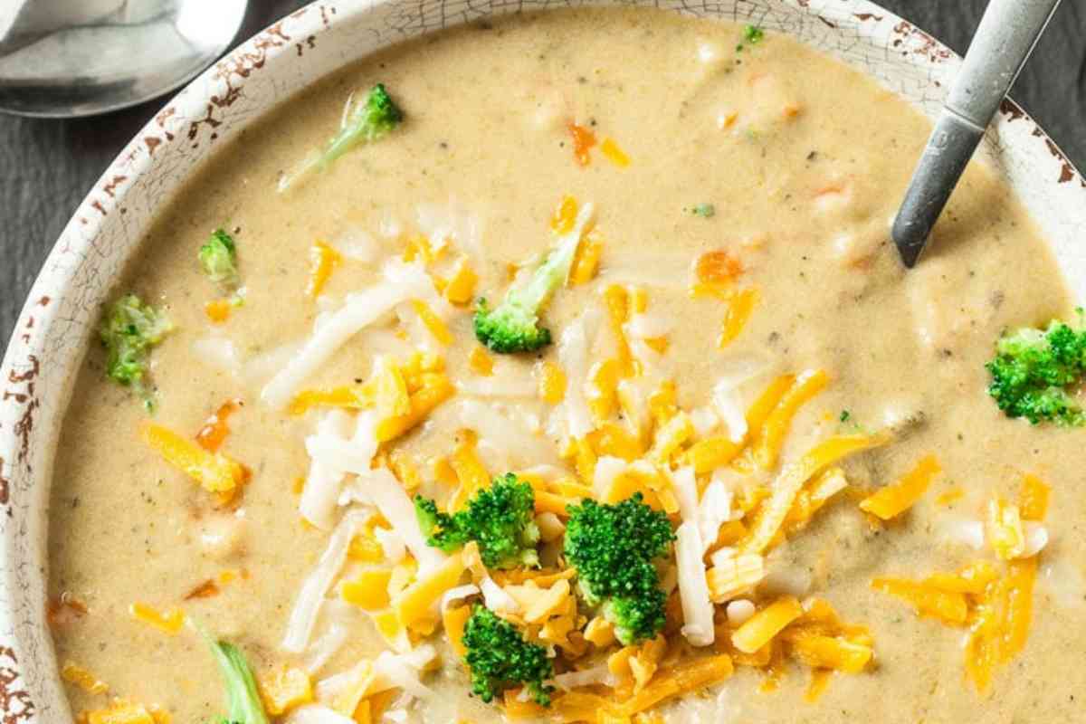 A bowl of broccoli cheddar soup with a spoon.