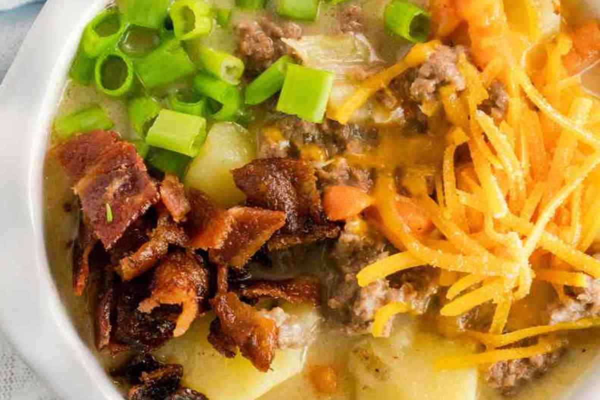 Instant Pot cheeseburger soup with crumbled bacon, scallions, and shredded cheese.