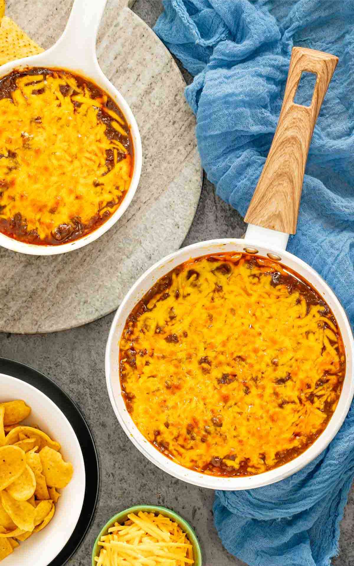 Overhead skyline chili dip picture with a serving bowl and frito scoops.
