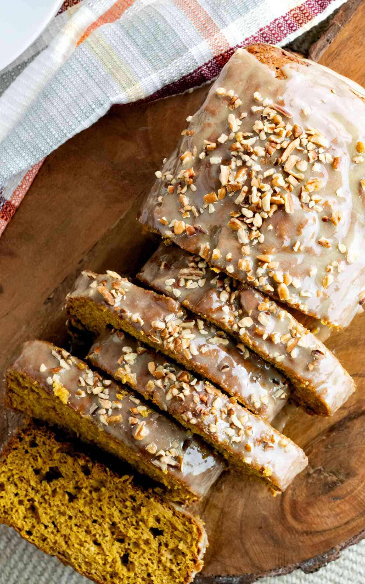 Overhead photo of iced pumpkin bread loaf with chopped pecans.
