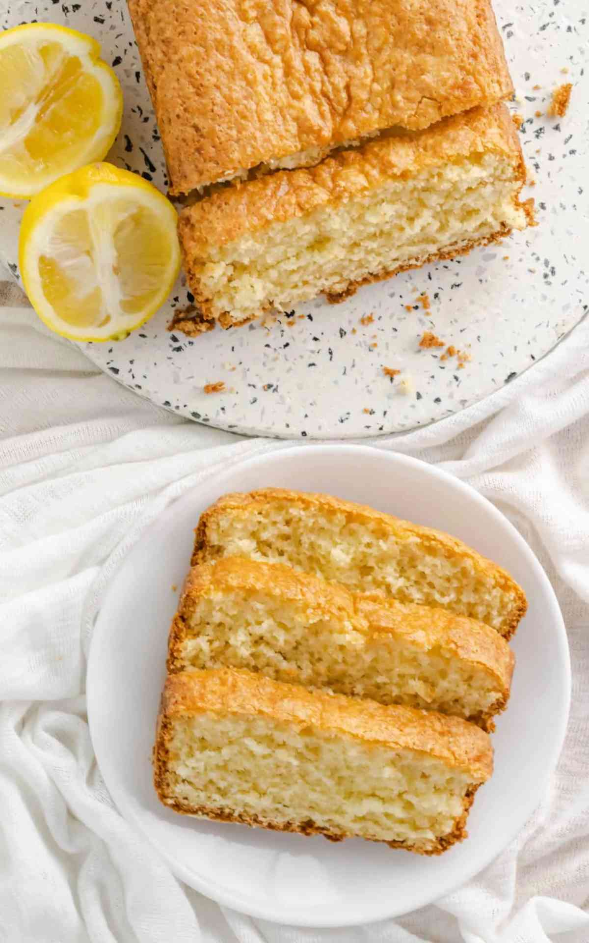 Overhead picture of slices of lemon loaf on a plate with fresh lemons next to it.