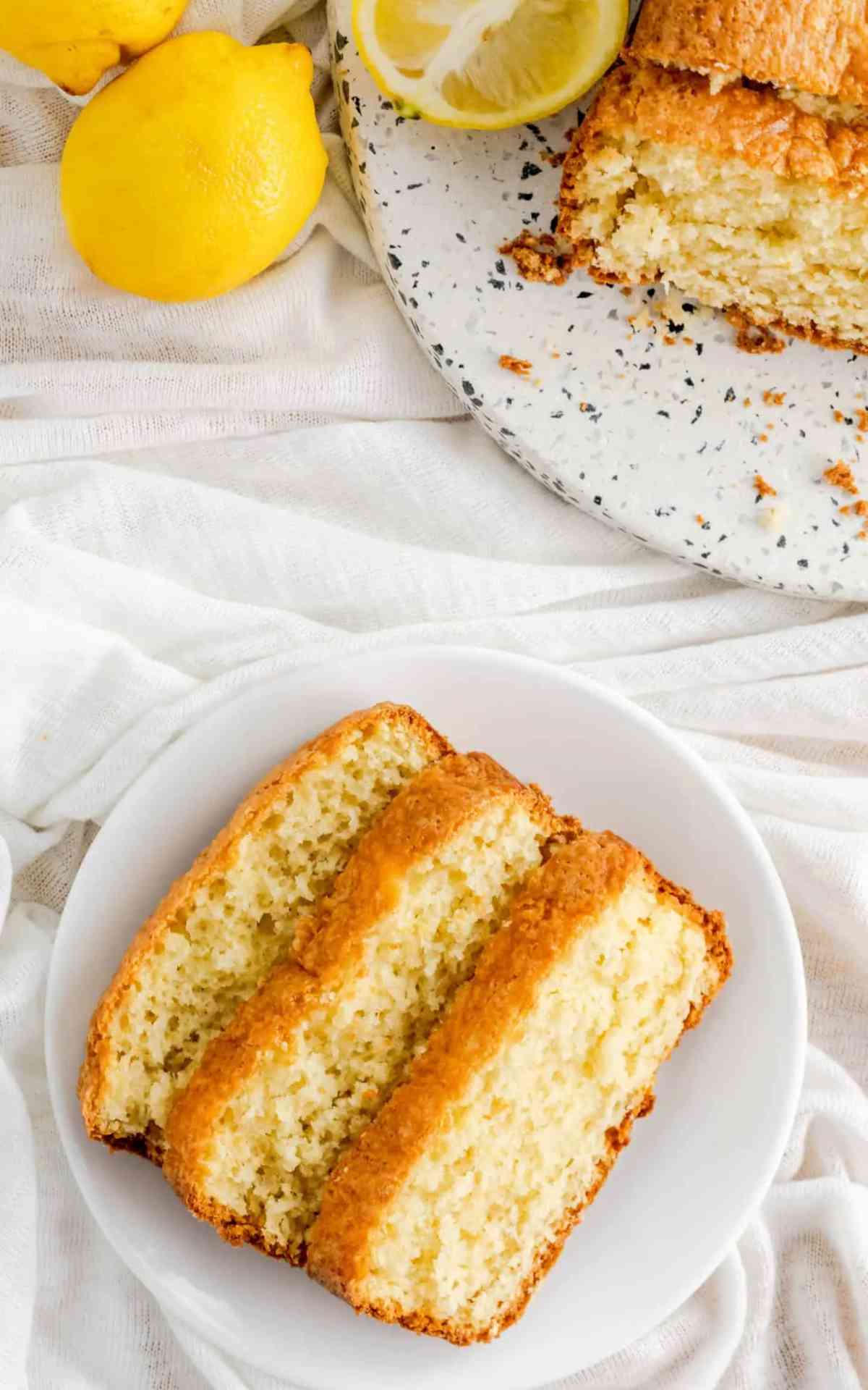 Overhead picture of slices of lemon quick bread on a plate with fresh lemons next to it.
