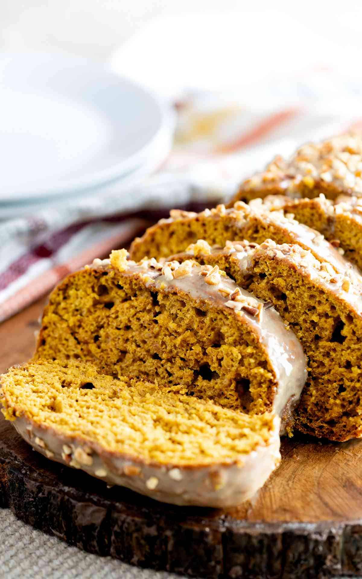 Sliced pumpkin bread loaf with caramel icing and chopped pecans.