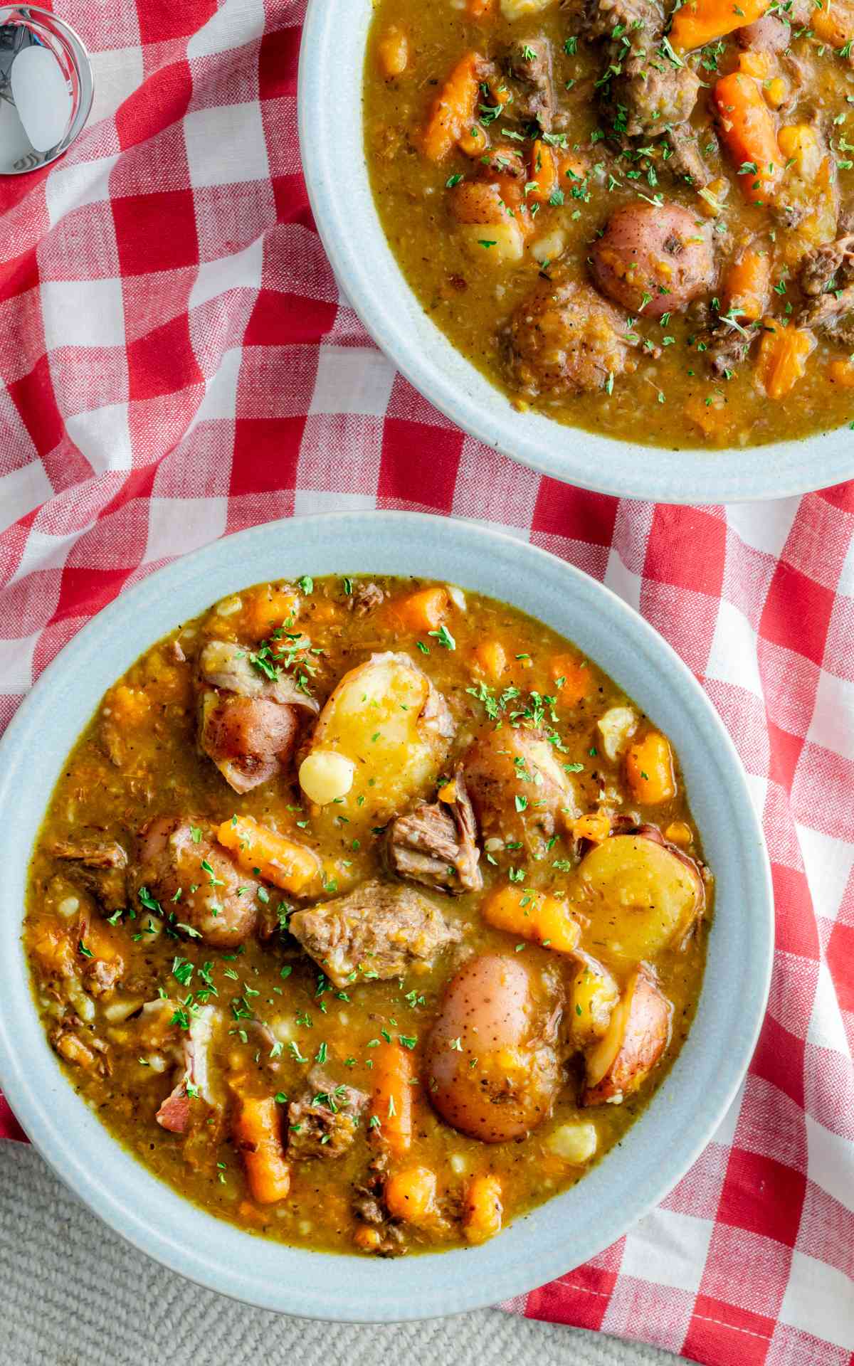 Two bowls of Instant Pot Beef Stew on red and white linen.