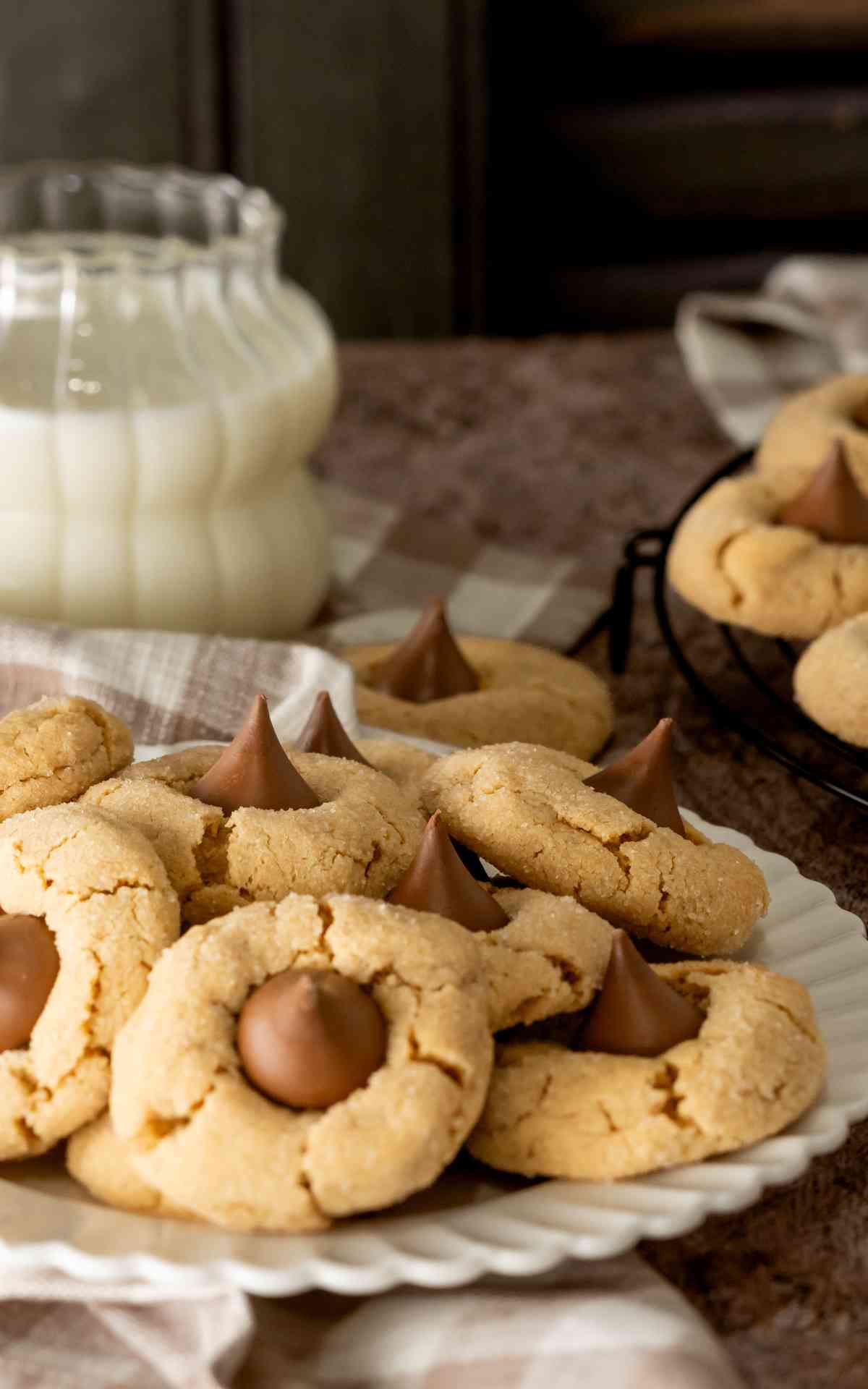 Peanut butter blossoms on a white plate with a glass of milk.