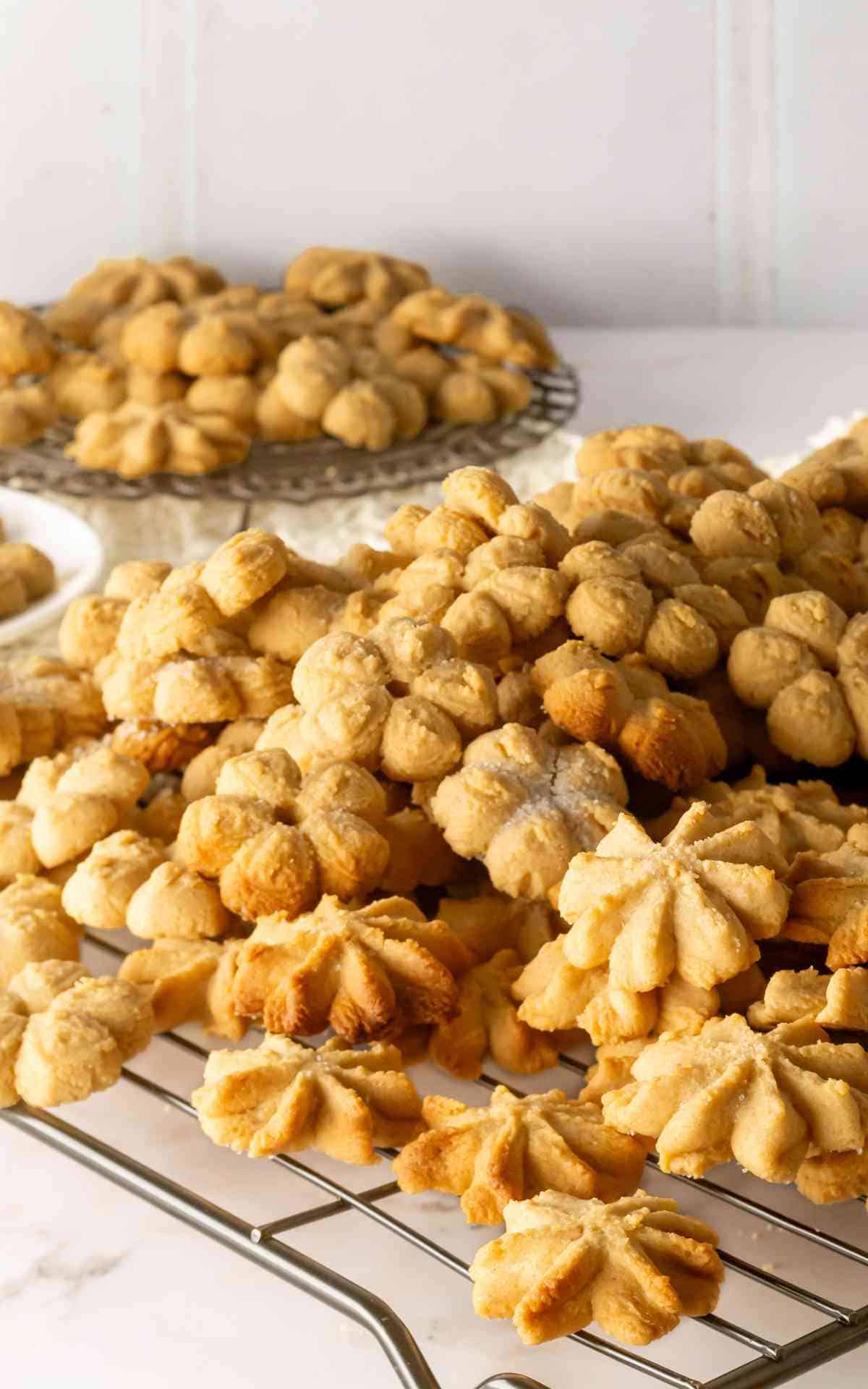 Peanut butter spritz cookies stacked on a cooling rack.