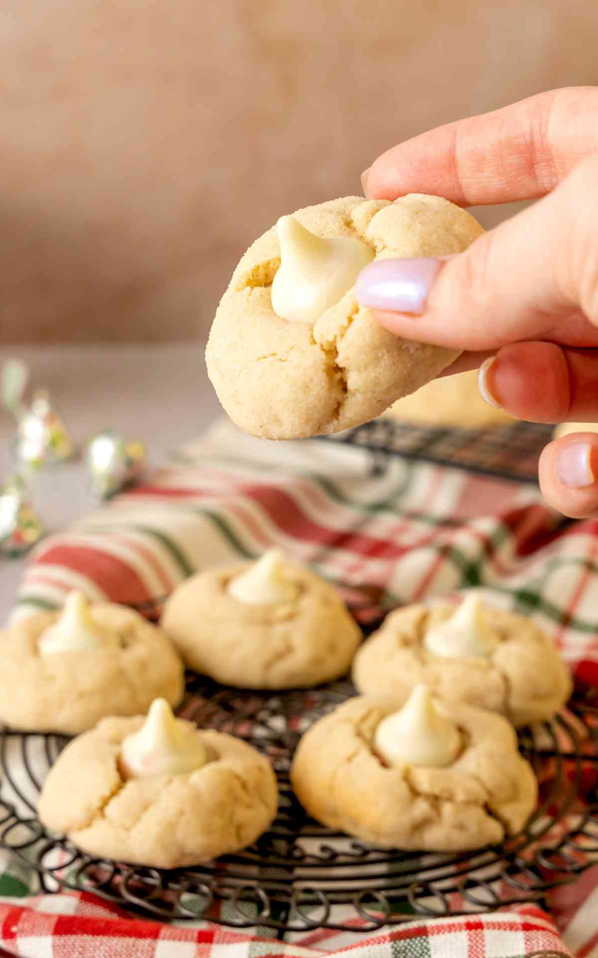 A manicured hand holding a sugar cookie blossom cookie.