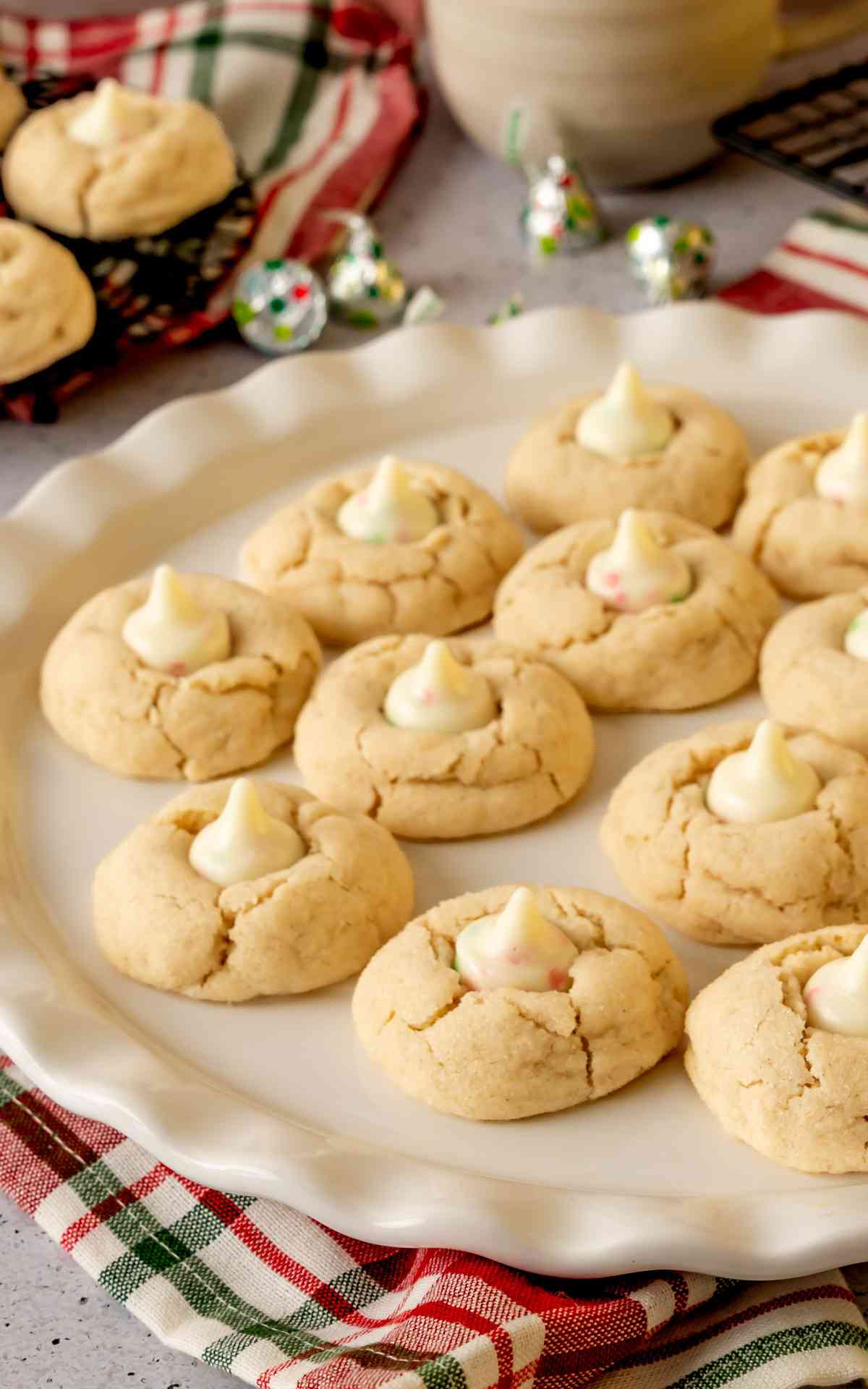 A serving plate on Christmas linen with sugar cookie blossoms on it.