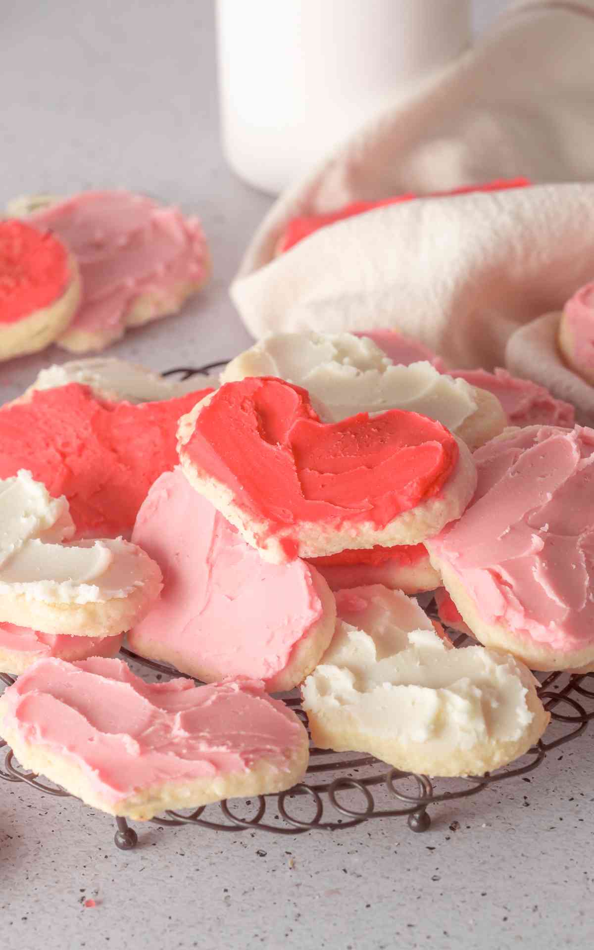 A decorative wire rack with stacked cream cheese sugar cookies.