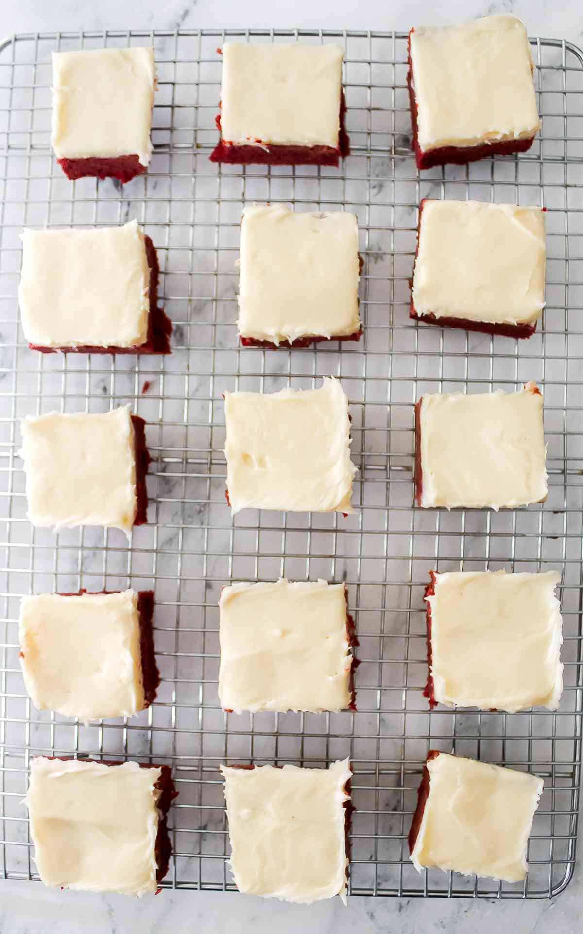 Red Velvet Bars frosted with cream cheese frosting on a wire rack.