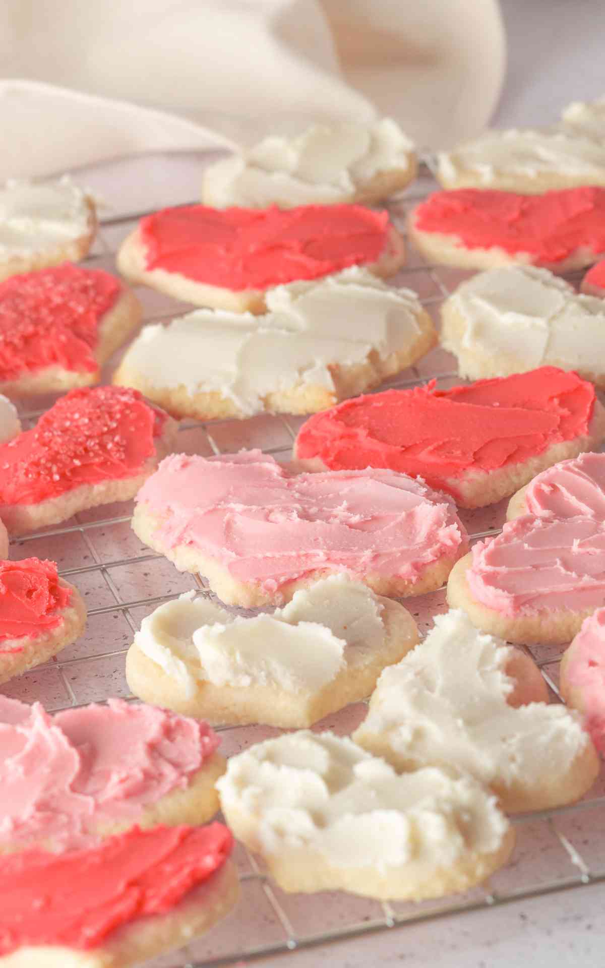 Valentine Day sugar cookies with buttercream frosting on a wire rack.