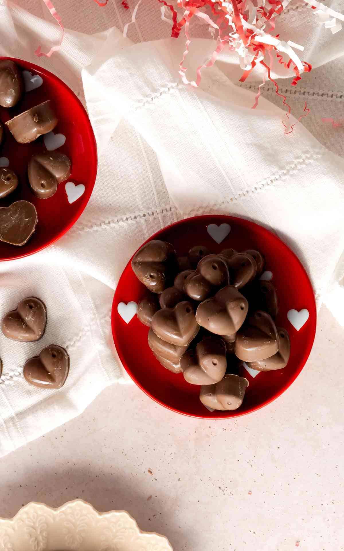 A red Valentine's Day plate with heart shaped chocolate candies.