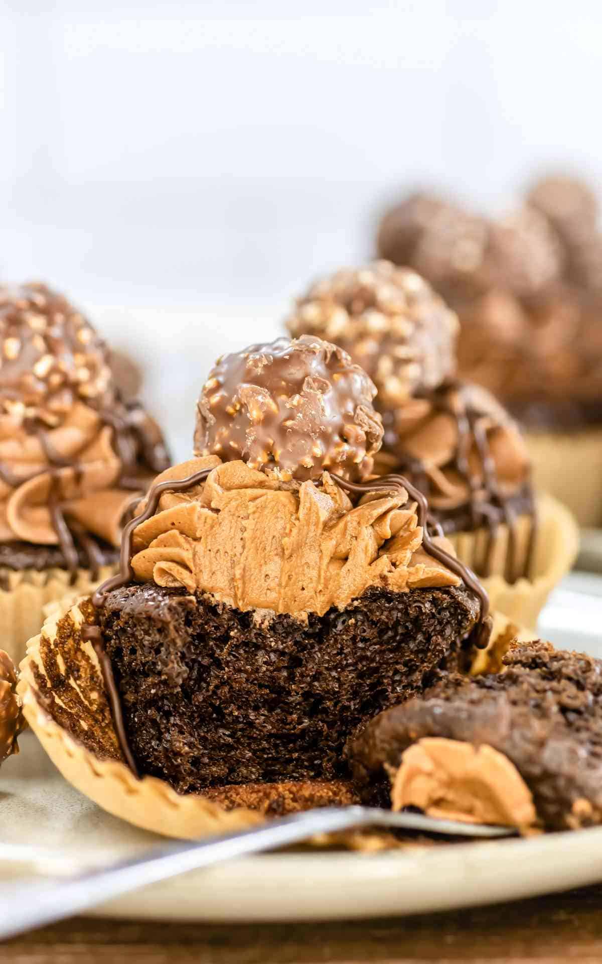 A chocolate cupcake with chocolate buttercream on a plate with a chocolate candy on top.