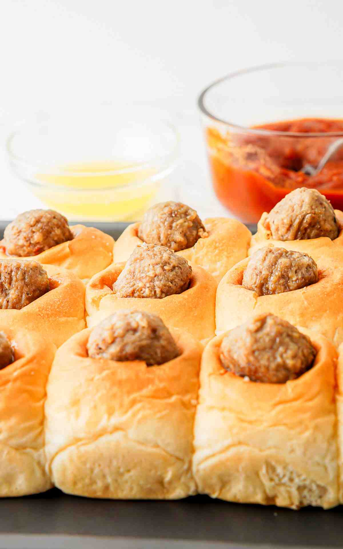 Hawaiian roll meatball sliders with meatballs set in the center of the rolls.