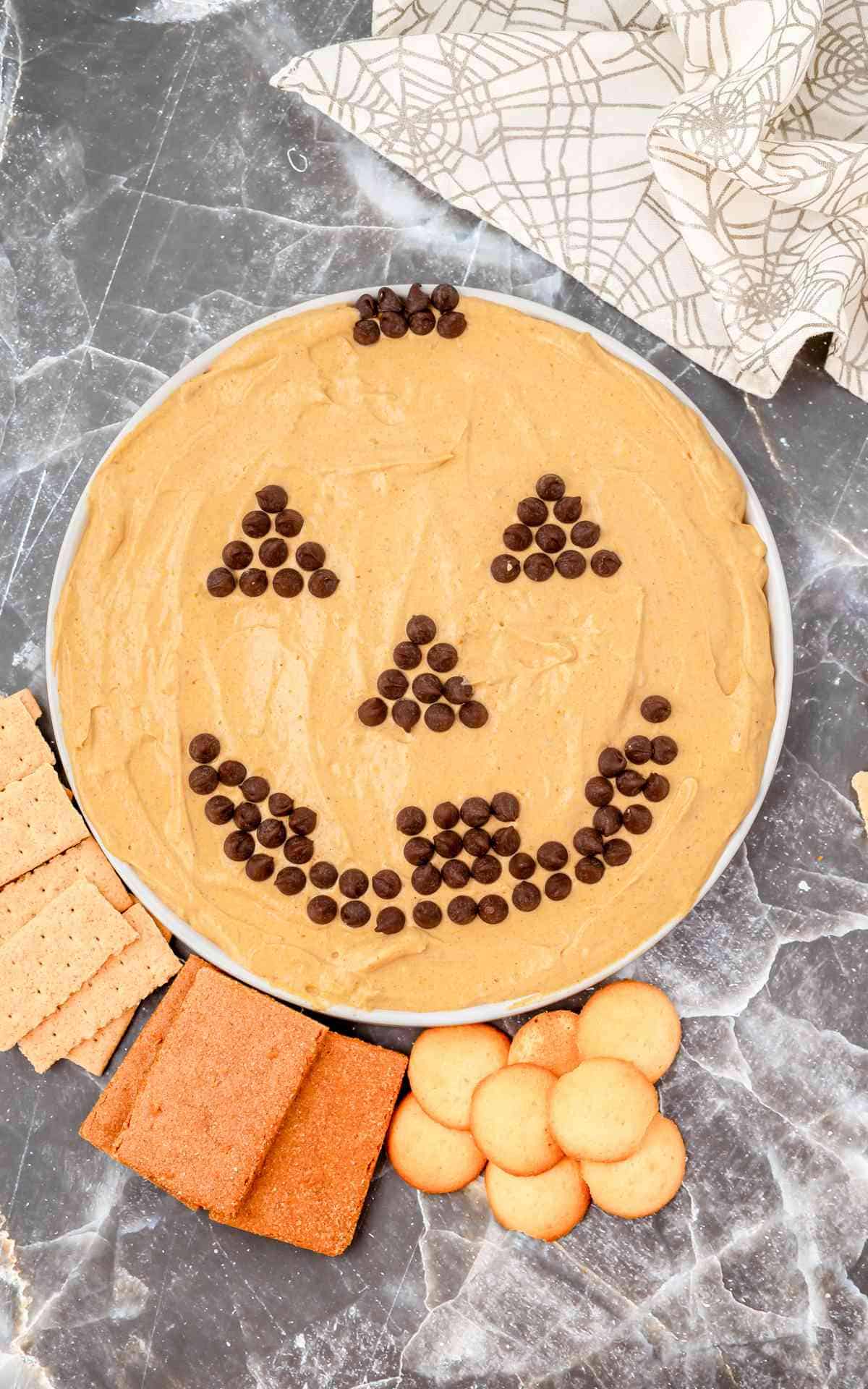 Jack O Lantern make out of chocolate chips on a bowl of fluffy pumpkin dip.