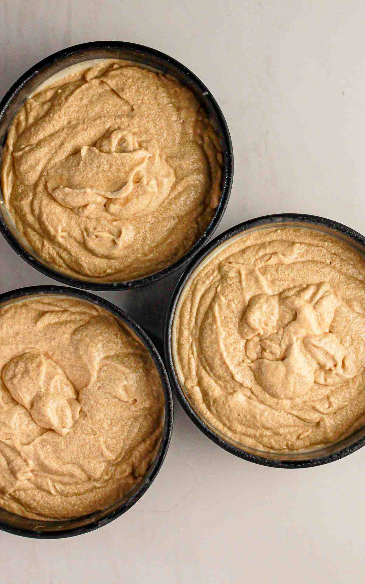 Three six inch cake pans with cake batter.