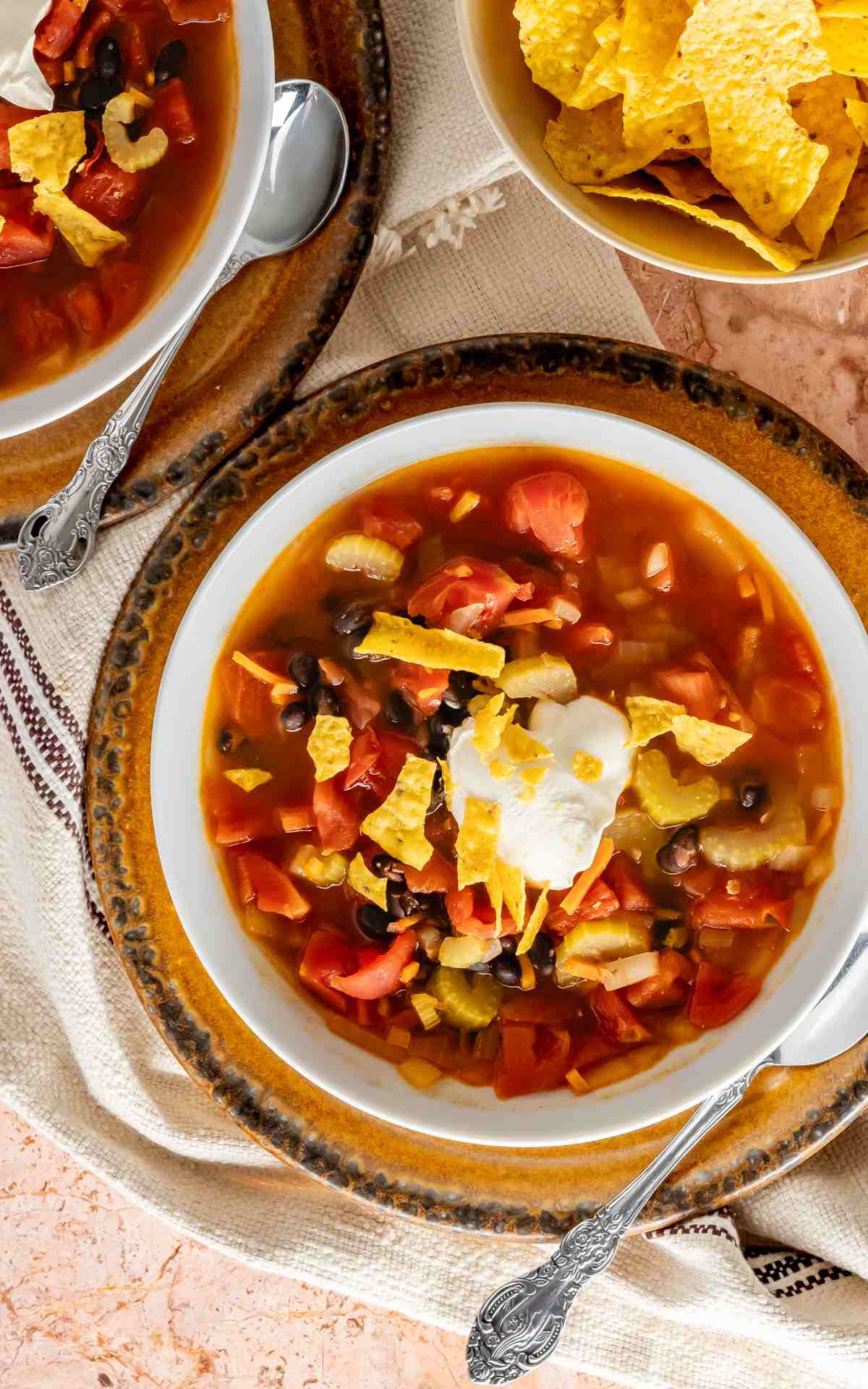 A bowl of Mexican black bean soup topped with sour cream and tortillas.