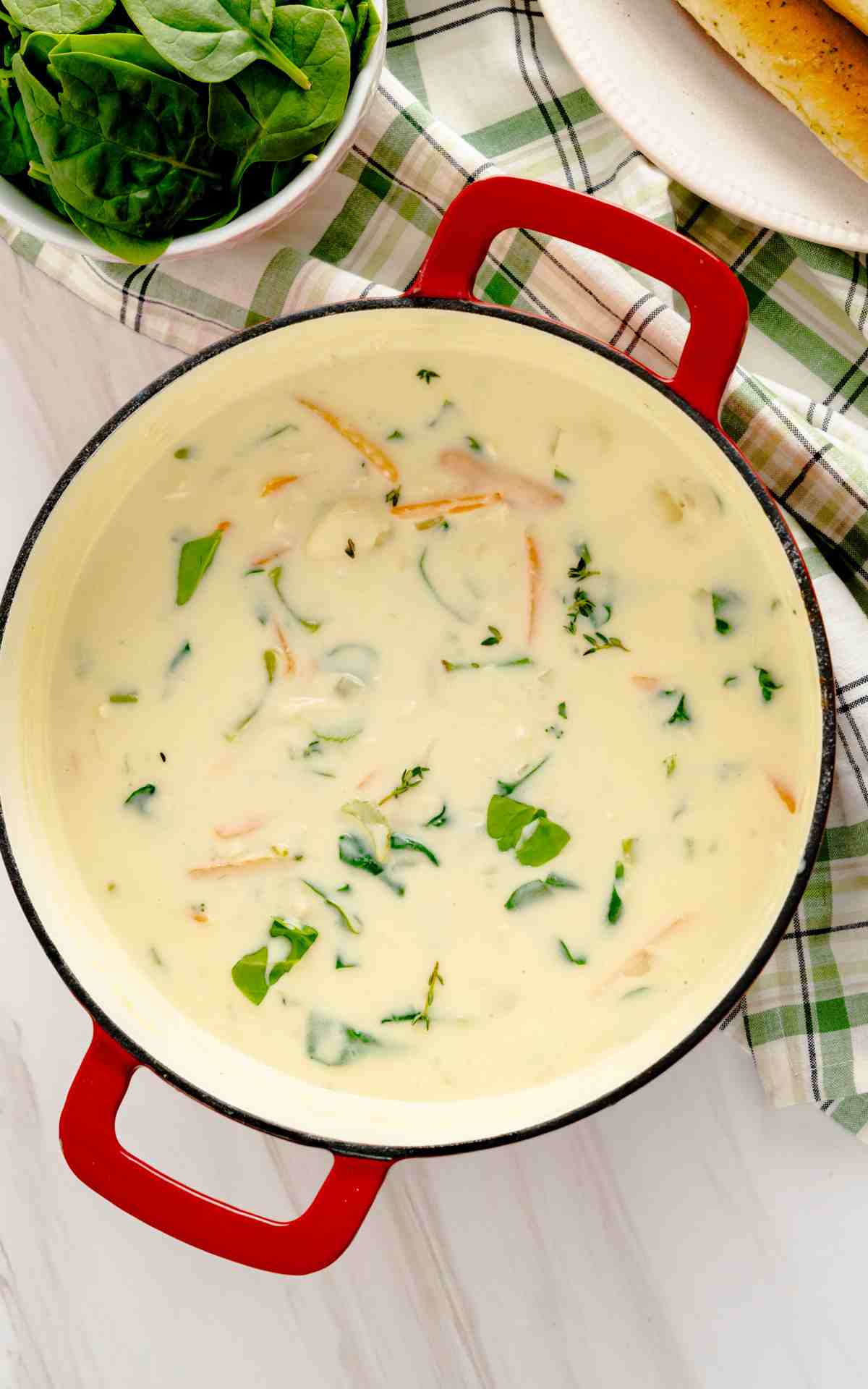 A red pot filled with homemade creamy chicken gnocchi soup.