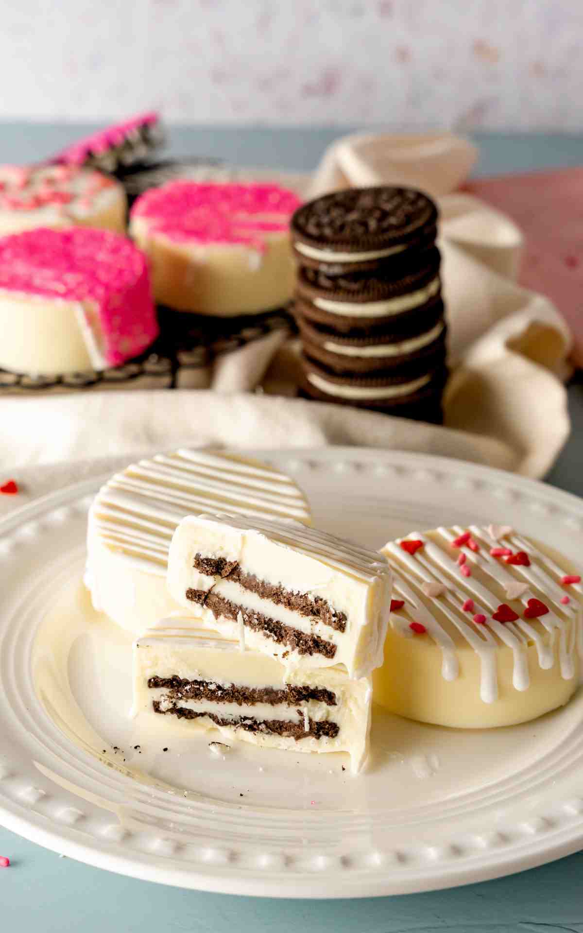 A white chocolate covered Oreo cut in half on a plate to see cookie inside.