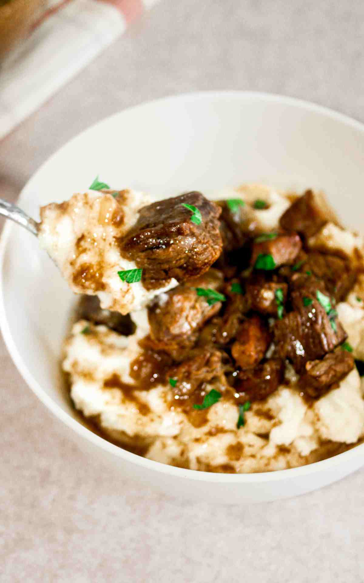 A bowl with mashed potatoes and beef tips in gravy made in the slow cooker.