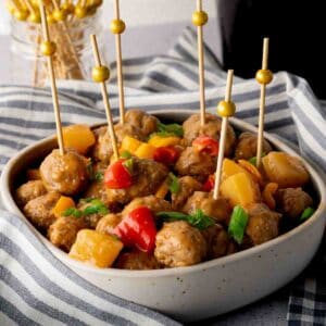Sweet and sour meatballs in a bowl with cocktail picks.