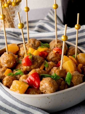 Sweet and sour meatballs in a bowl with cocktail picks.