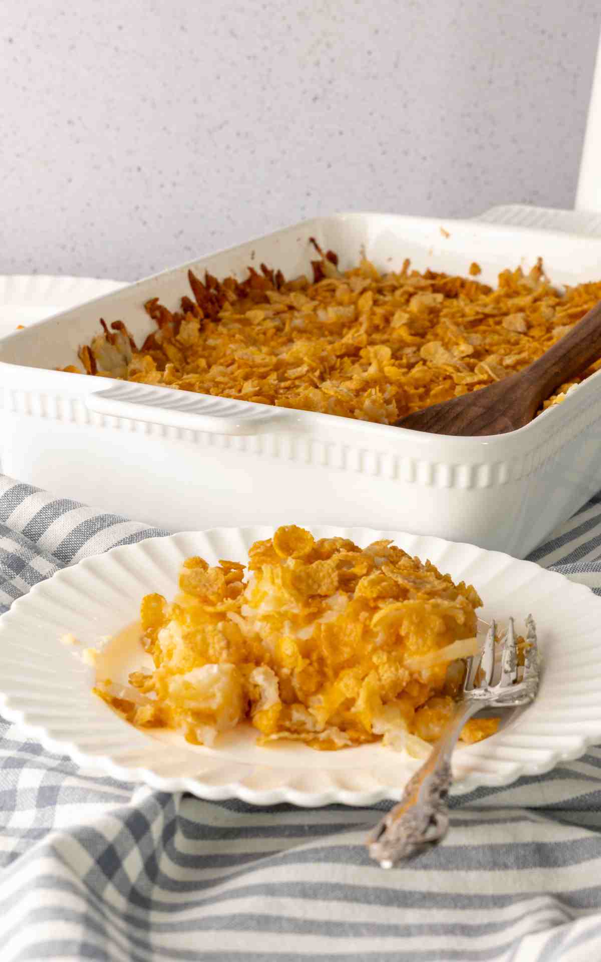 A plate with a serving of cheesy potato casserole made with hashbrowns.