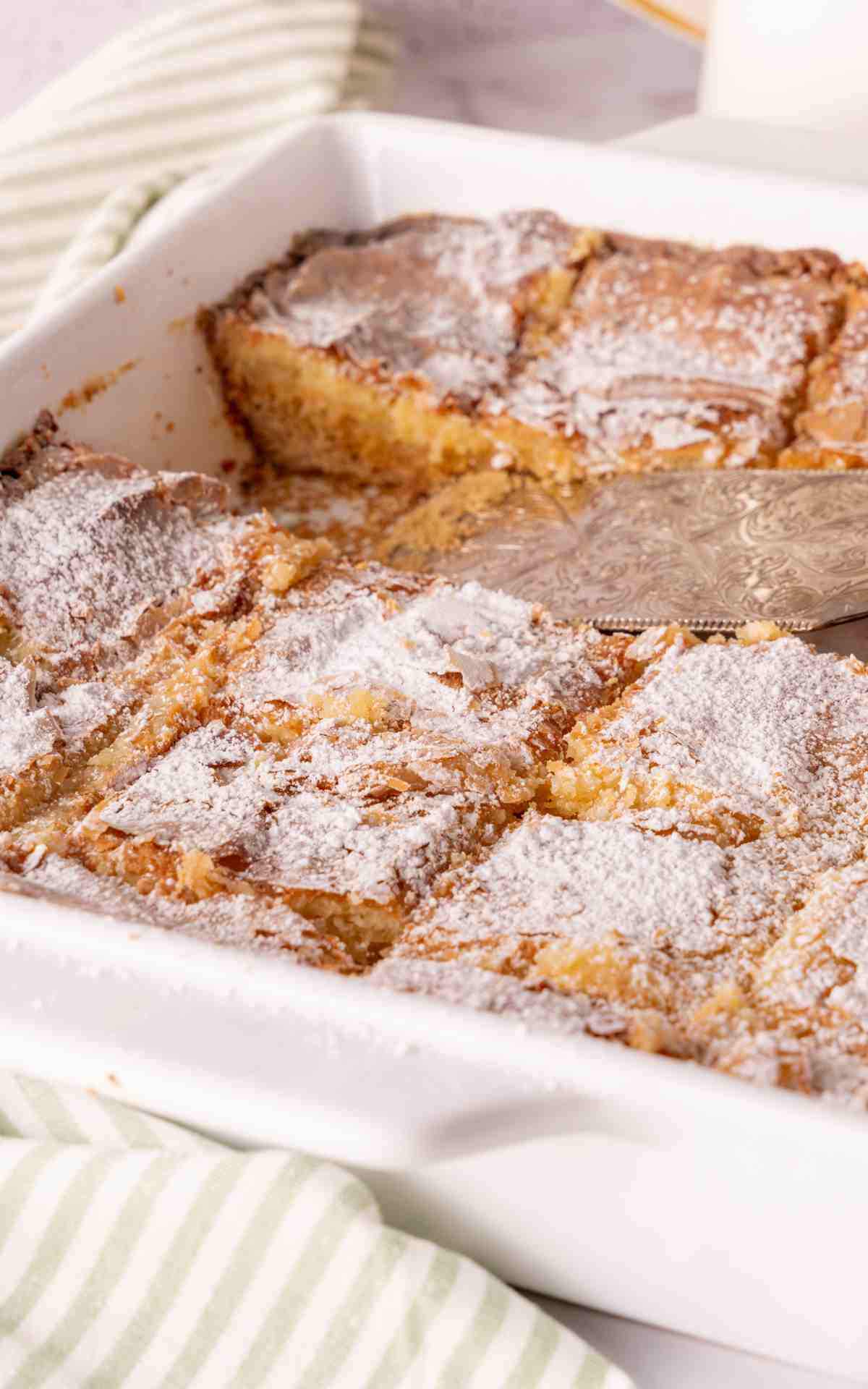 Cut squares of cream cheese butter cake in a white baking dish.