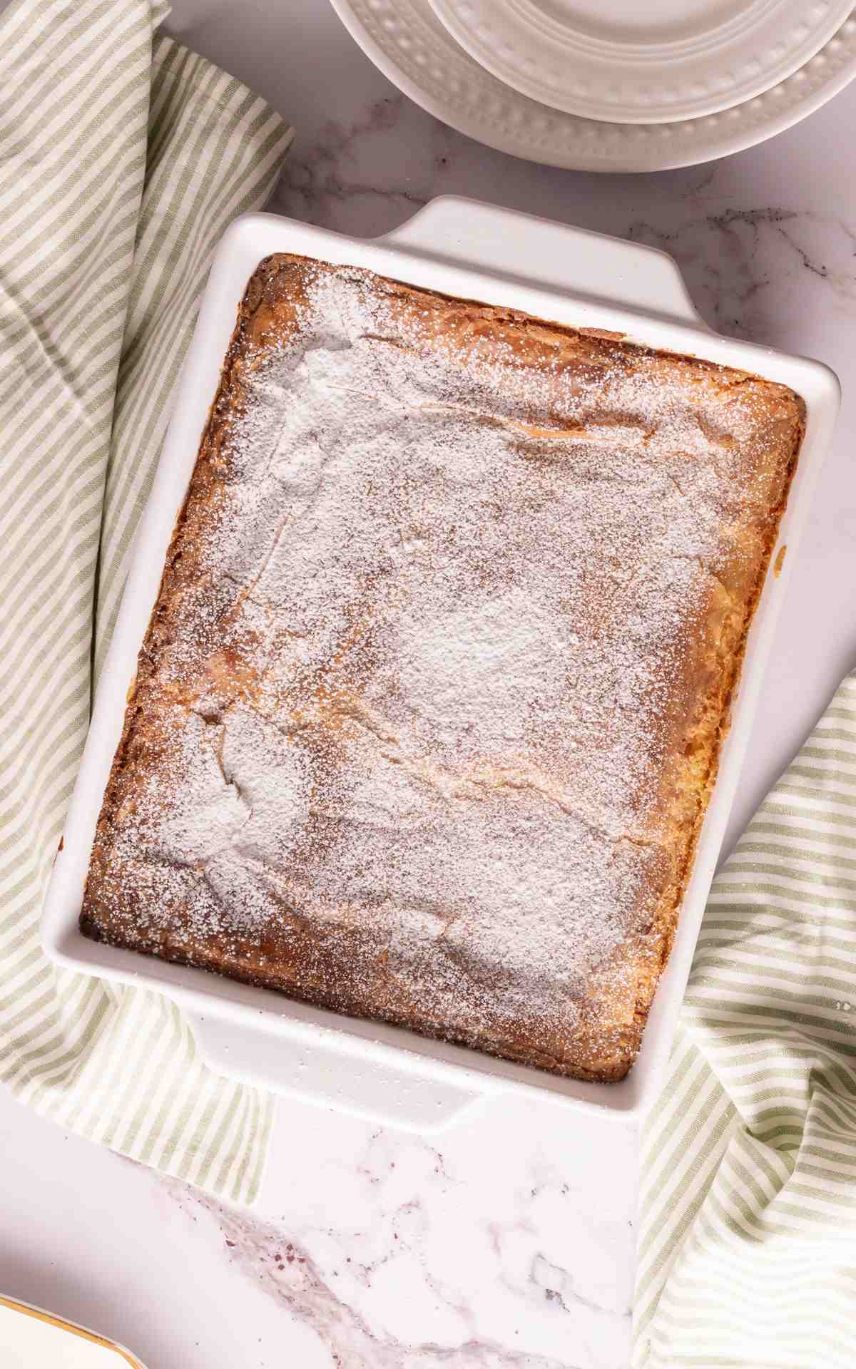 Gooey butter cake dusted with powdered sugar in a baking dish.
