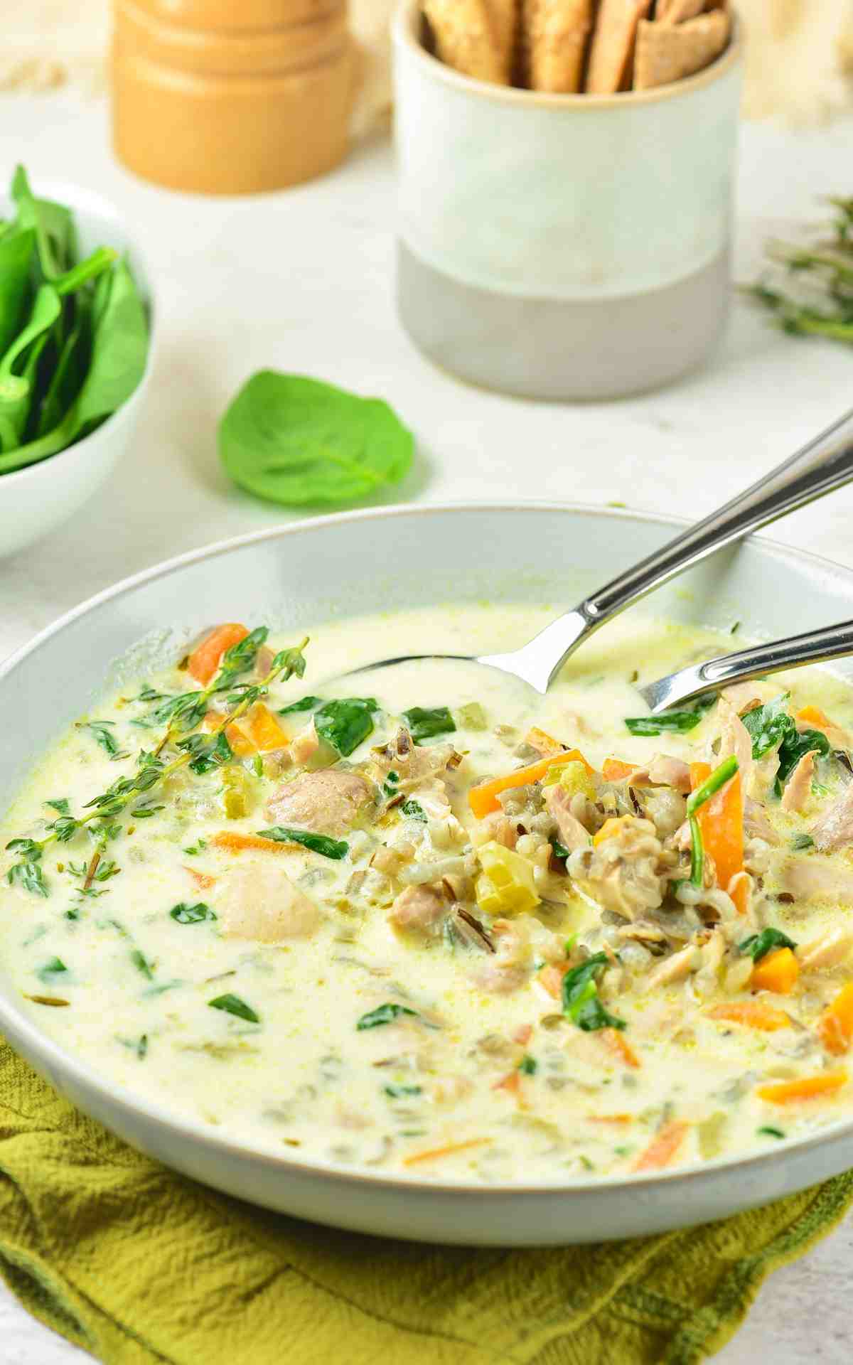 Spoons in a bowl of chicken and wild rice soup with a creamy broth.