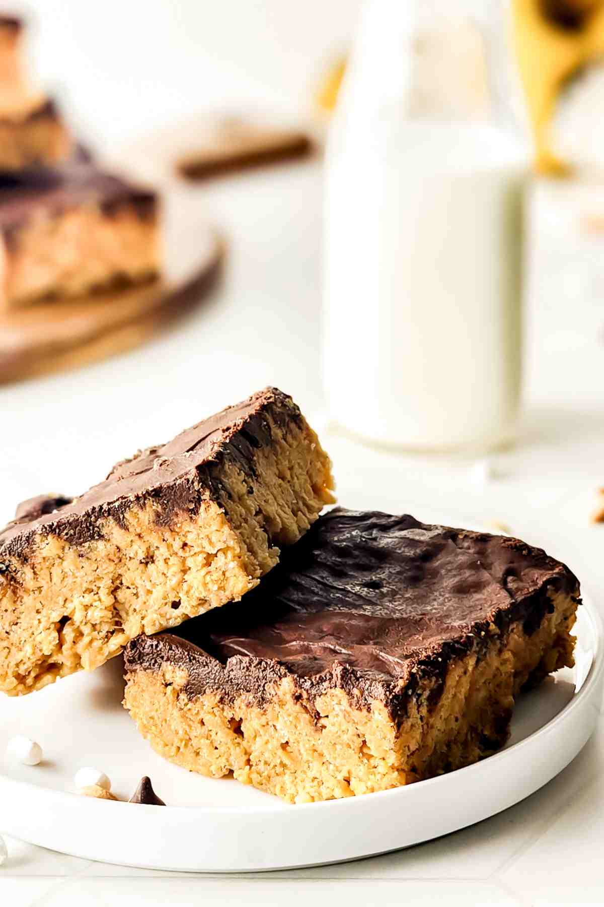 Two peanut butter rice krispies treats on a plate topped with chocolate.