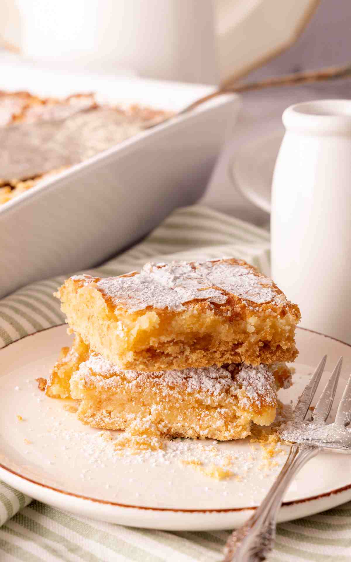 Two slices of cream cheese gooey butter cake stacked on a plate.