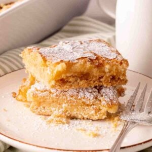 Two slices of gooey butter cake stacked on a plate with a fork.